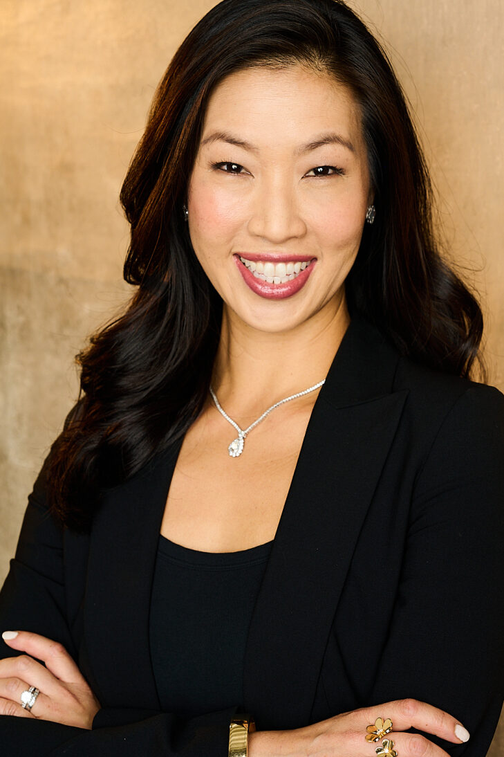 Denise Lee has dark hair and is wearing a black suit