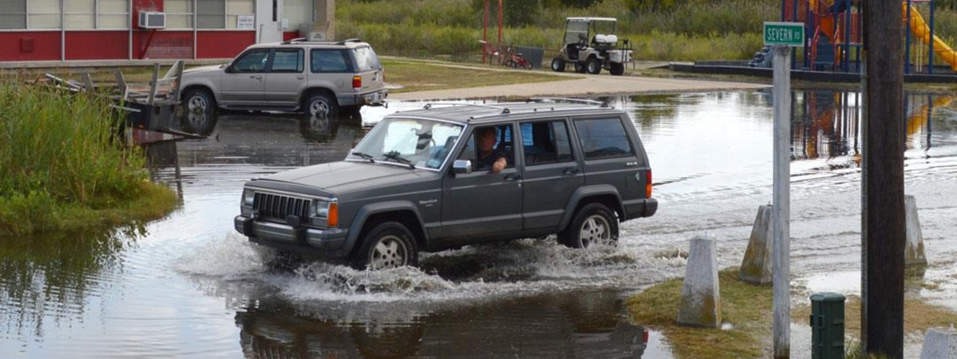 A resident drives his car through hub-cap deep water on a street