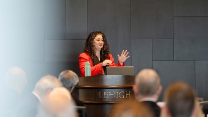 A speaker stands at a podium and addresses a crowd of people.