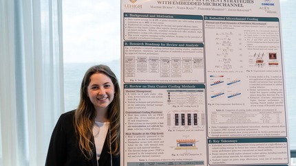 A smiling student poses next to a large research poster filled with small text and charts.